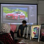Students in a classroom working on a Photoshop tutorial