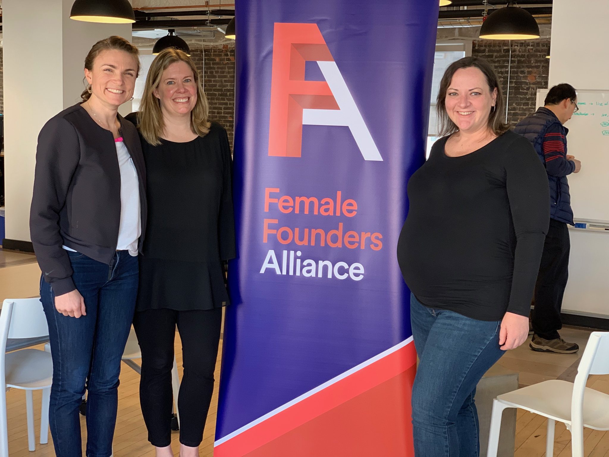 Director of Operations Rohre Titcomb, Vice President of Business Alliances Samantha Agee and CEO Leslie Feinzaig stand with a Female Founders Alliance banner