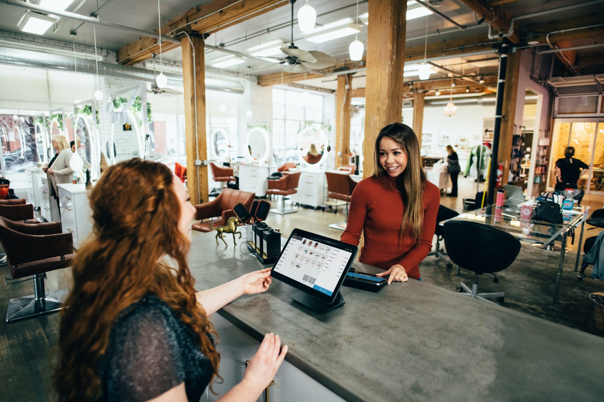 Woman using point-of-sales system to pay small business owner. Photo by Blake Wisz on Unsplash.