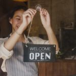 A store manager changing a sign from closed to open